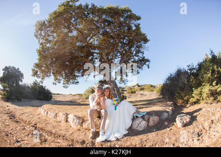 Newlywed couple sitting under a tree in summer Stock Photo