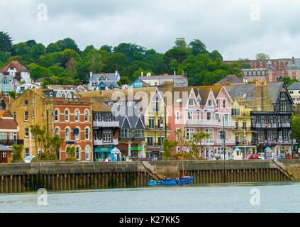 Coastal town of Dartmouth with brightly coloured buildings at foot of tree-cloaked hillside beside harbour and wharf in Devon, England Stock Photo