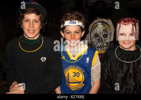 Halloween teen boys dressed as sports guys, bloody guy and skeleton in costumes trick and treating. St Paul Minnesota MN USA Stock Photo