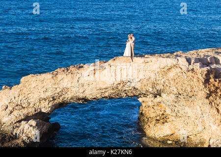 beautiful gorgeous blonde bride and stylish groom kissing on rocks, on the background of a sea, wedding ceremony on cyprus. Stock Photo