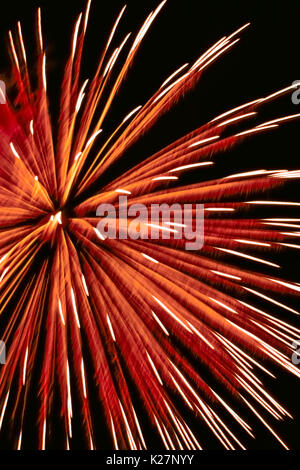 An aerial firework explodes with a shower of feathery streaks created by gunpowder in a pyrotechnic device that was shot into a dark sky that is the background for this aesthetic display. Stock Photo