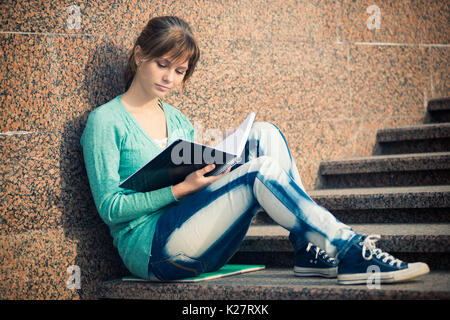 Girl sitting on stairs and reading note Stock Photo