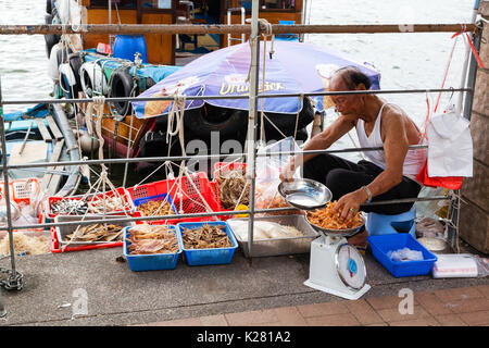 HONG KONG - JULY 13, 2017: A fisherman sells dried seafood along the pier at the Sai Kung floating seafood market in Hong Kong. Stock Photo