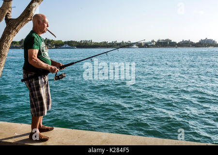 Miami Beach Florida,Bay Walk,marina,waterfront,man men male,fishing,smoking cigar,Hispanic senior seniors citizen citizens,Government Cut,FL170430243 Stock Photo