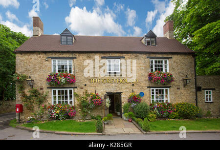 The Greyhound pub, historic 17th century building of Cotswold stone, with window boxes & hanging baskets with colourful flowers near Wootton, England Stock Photo