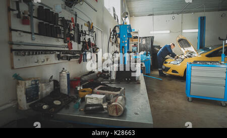 Mechanic in the garage, car preparing for repairing, wide angle Stock Photo