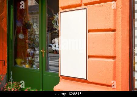 Signboard view of empty white mockup signage in frame with orange shop wall in background Stock Photo