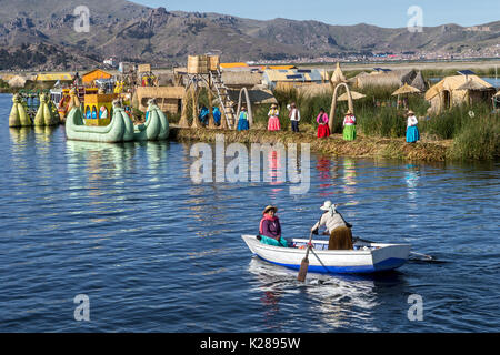 Uros floating Island made from totora reed with Puno in background Lake Titicaca Peru Stock Photo