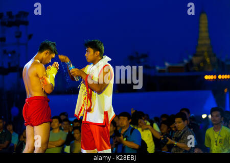 Bangkok, Thailand - April 10, 2007: Trainer pouring water over kickboxer during pre-fight ceremony at outdoor exhibition muay thai kickboxing match at Stock Photo