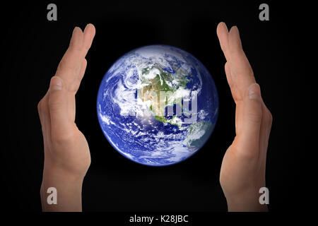 Glowing earth globe in hands on black background, environment concept - elements of this image furnished by NASA Stock Photo