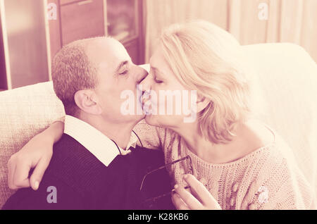 Portrait of loving elderly spouses sitting on sofa indoor Stock Photo