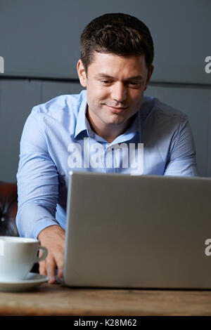 Businessman Working On Laptop In Internet Cafe Stock Photo