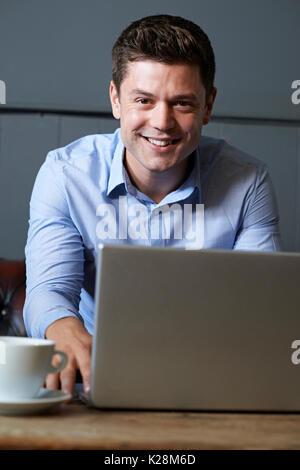Businessman Working On Laptop In Internet Cafe Stock Photo