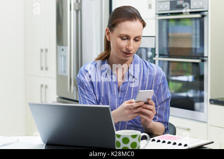 Female Freelance Worker Using Laptop In Kitchen At Home Stock Photo