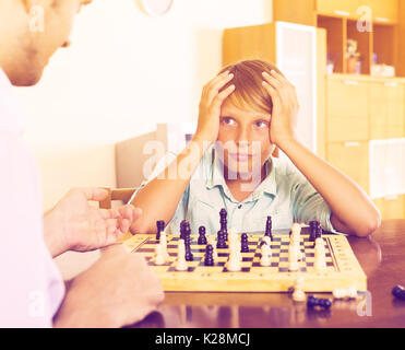 Father and son playing chess at home, boy losing Stock Photo