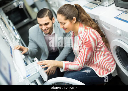 Happy young couple choosing washing machine in hypermarket Stock Photo