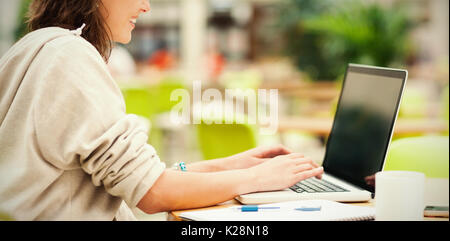 Side view of student using laptop at cafeteria table Stock Photo
