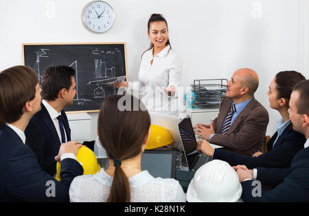 Team of successful energetic creative engineers and architects discussing business project and smiling indoors Stock Photo