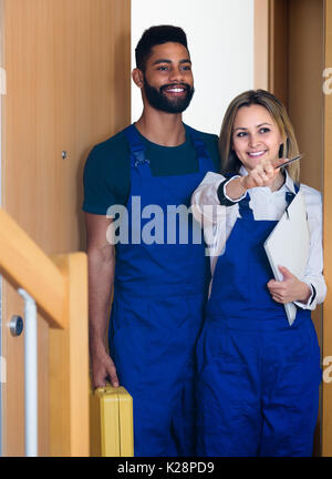 Professional workers with tools standing at doorway and smiling Stock Photo