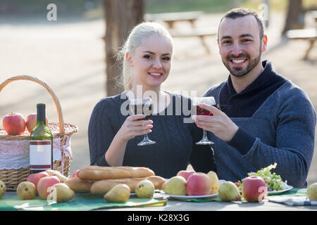 positive spanish couple having picnic in sunny spring day at countryside Stock Photo