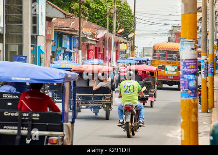 Very busy street in Iquitos, Peru. The popular mototaxis, a type of rickshaw, is the most popular form of the public transport in the city. Stock Photo