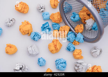 Colorful crumpled paper balls rolling out of a trash can. Idea Concept. Stock Photo