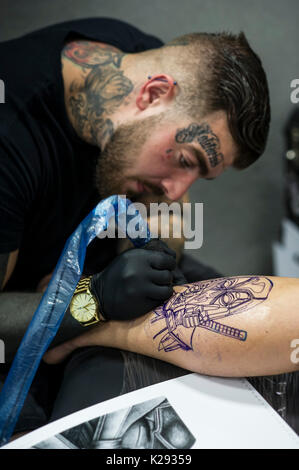 Cornwall Tattoo Convention - Luke Rudden tattooing a design on the leg ...