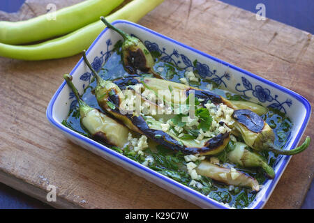 Green pepper salad on wooden cutting board - baked green peppers with garlic and parsley in olive oil salad Stock Photo