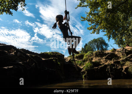 Girl on river swing Stock Photo