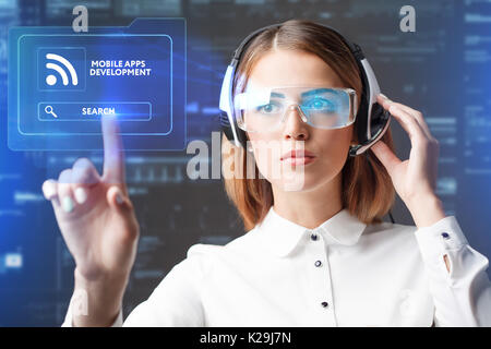 Young businesswoman working in virtual glasses, select the icon mobile apps development on the virtual display. Stock Photo