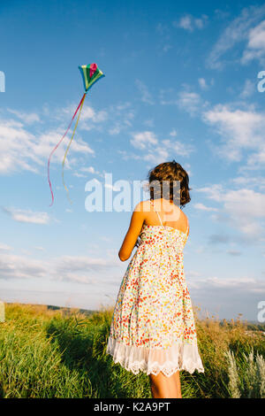 Girl playing with kite in field Stock Photo