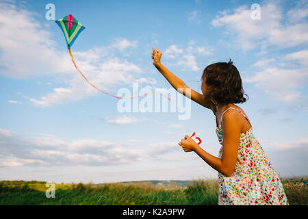Girl playing with kite in field Stock Photo