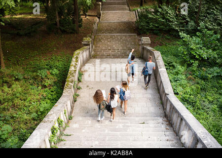 Teenage students walking on stone steps in front of university. Stock Photo