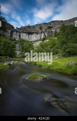Scenic summer evening view of swirling water of Malham Beck & the Cove, a huge, curving limestone cliff - Malhamdale, Yorkshire Dales, England, UK. Stock Photo