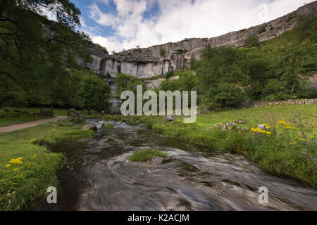 Scenic summer evening view of swirling water of Malham Beck & the Cove, a huge, curving limestone cliff - Malhamdale, Yorkshire Dales, England, UK. Stock Photo