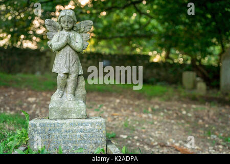 Old praying stone angel statue on a cemetery in the UK Stock Photo