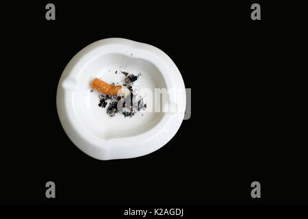 smoked cigarette in white ashtray isolated on black background Stock Photo