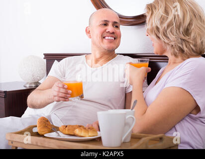 Happy mature spouses having healthy breakfast in bed in the morning Stock Photo