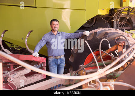 portrait of happy male farmer having a break near huge tractor Stock Photo