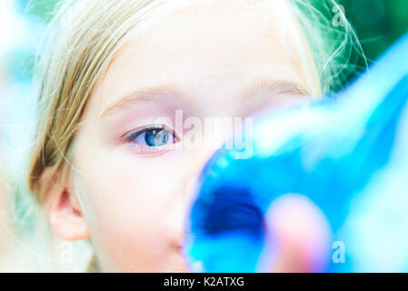 Cute little girl drinking water in a summer garden Stock Photo