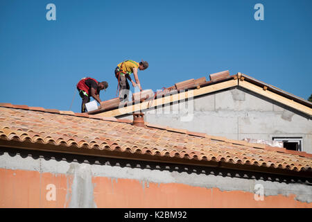 Roofers at work installing tiles on a new home in Provence, France Stock Photo