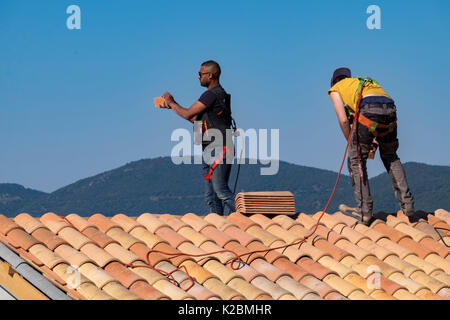 Roofers at work installing tiles on a new home in Provence, France Stock Photo