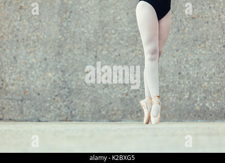 Closeup shot of legs of a female ballet dancer standing on her toes wearing pointe shoes. Ballet dancer practicing dance moves. Stock Photo