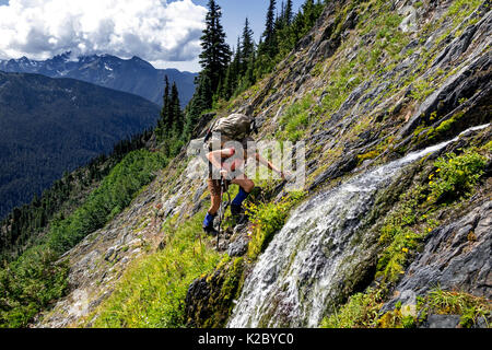 Hiker crossing a steep slope on the Bailey Range Traverse in Olympic National Park, Washington, USA, August 2014. Model released. Stock Photo