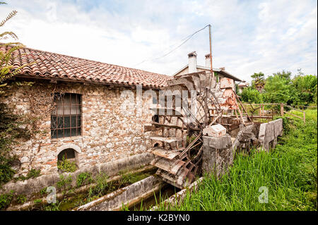 Old water mill with iron water wheel. Stock Photo