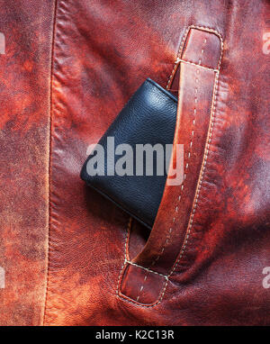 Black wallet sticking out of the pocket of the red jacket made of leather Stock Photo