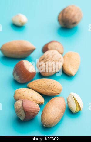 Different types of nuts in the nutshell on blue background. Dried nuts. Stock Photo