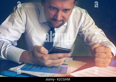 Angry businessman reading message in a smartphone. Problems in a business. Stock Photo