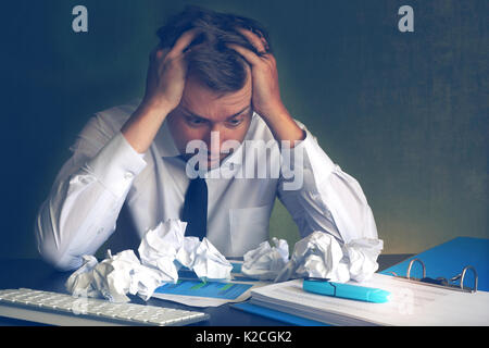 Scared business man looking on crumpled office paper. Stress and paperwork. Stock Photo