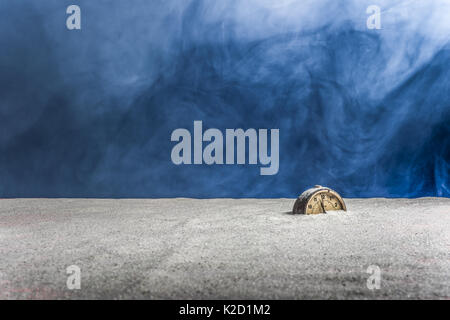 Abstraction: An ancient alarm clock buried in white sand on a blue background and fog Stock Photo